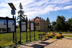 Tablice historyczne, w tle pomarańczowy budynek