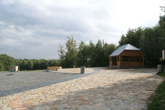Drewniana wiata pokryta dachem z blachy na placu z płyt kamiennych