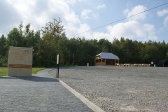 Duży plac wysypany klińcem, z lewej toaleta, w dali wiata drewniana