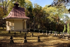 Kaplica cmentarna z czerwonym dachem pośród mogił żołnierskich