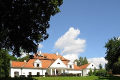 Biały dworek z czerwonym dachem na tle błękitnego nieba