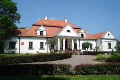 Biały dworek z czerwonym dachem na tle błękitnego nieba