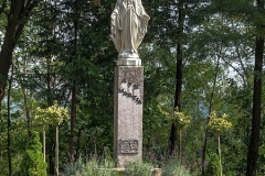 Biała figura Matki Bożej na kamiennym postumencie