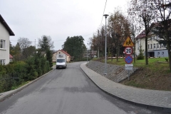 Droga asfaltowa prowadząca do szkoły, z prawej znak drogowy ograniczający prędkość i informujący o przechodzących dzieciach