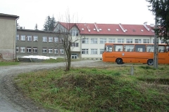 Pomarańczowy autobus szkolny na tle budynków szkolnych