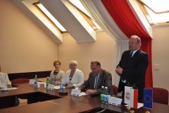Stanisław Sorys przemawia w pozycji stojącej na tle biało-czerwonej flagi