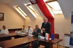 Stanisław Sorys przemawia w pozycji stojącej na tle biało-czerwonej flagi