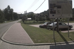 Chodnik z czerwonej kostki brukowej obok parkingu, na którym stoją samochody