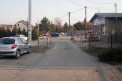 Wąska droga obok sklepu, a lewej zaparkowany samochód