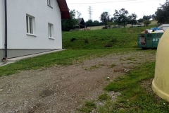 Boczna ściana budynku, z prawej strony kontener na śmieci