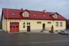 Żółty budynek z czerwonym dachem i czerwoną bramą garażową