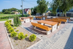 Betonowo-drewniane ławeczki na placyku z kostki brukowej