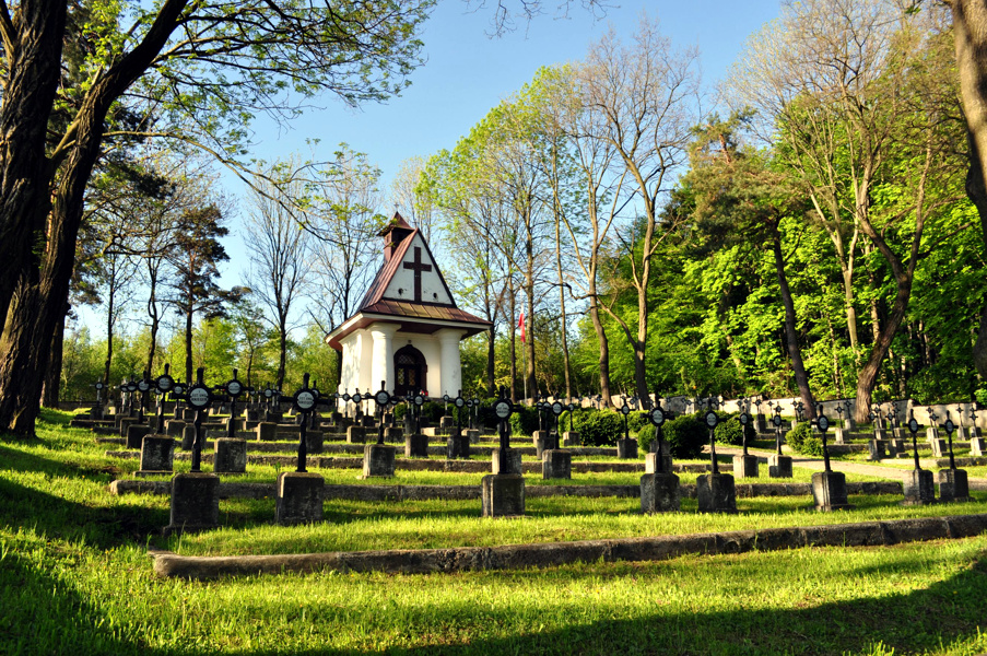 Cmentarz Legionistów w Łowczówku, groby żołnierzy pośród drzew, z tyłu kaplica