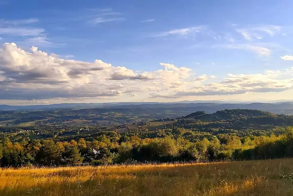 Panorama Gminy Pleśna - widok wzgórz i lekko pochmurzonego nieba