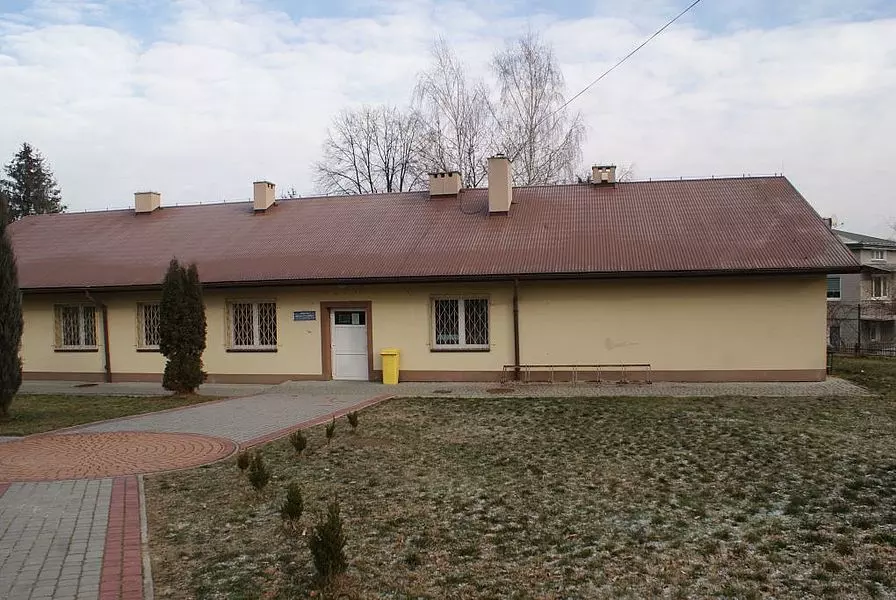 Niski budynek z czerwonym dachem - Punkt Pomocy Prawnej w Gminie Pleśna
