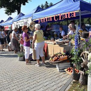 Stragany na rynku i ludzie odwiedzający stoiska.