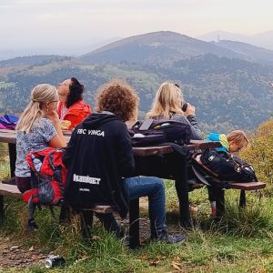 Zdjęcie przedstawia grupę osób odpoczywającą przy stoliku w górach