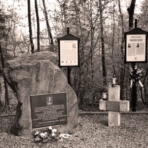 Zdjęcie przedstawia upamiętniający obelisk, betonowy krzyż oraz tablice upamiętniające lokalnych bohaterów