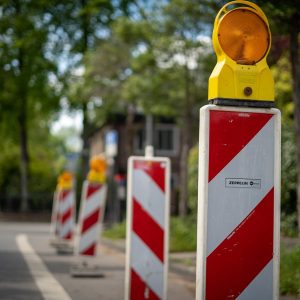 Czerwono białe znaki z pomarańczowym światłem ostrzegawczym, informujące o robotach drogowych
