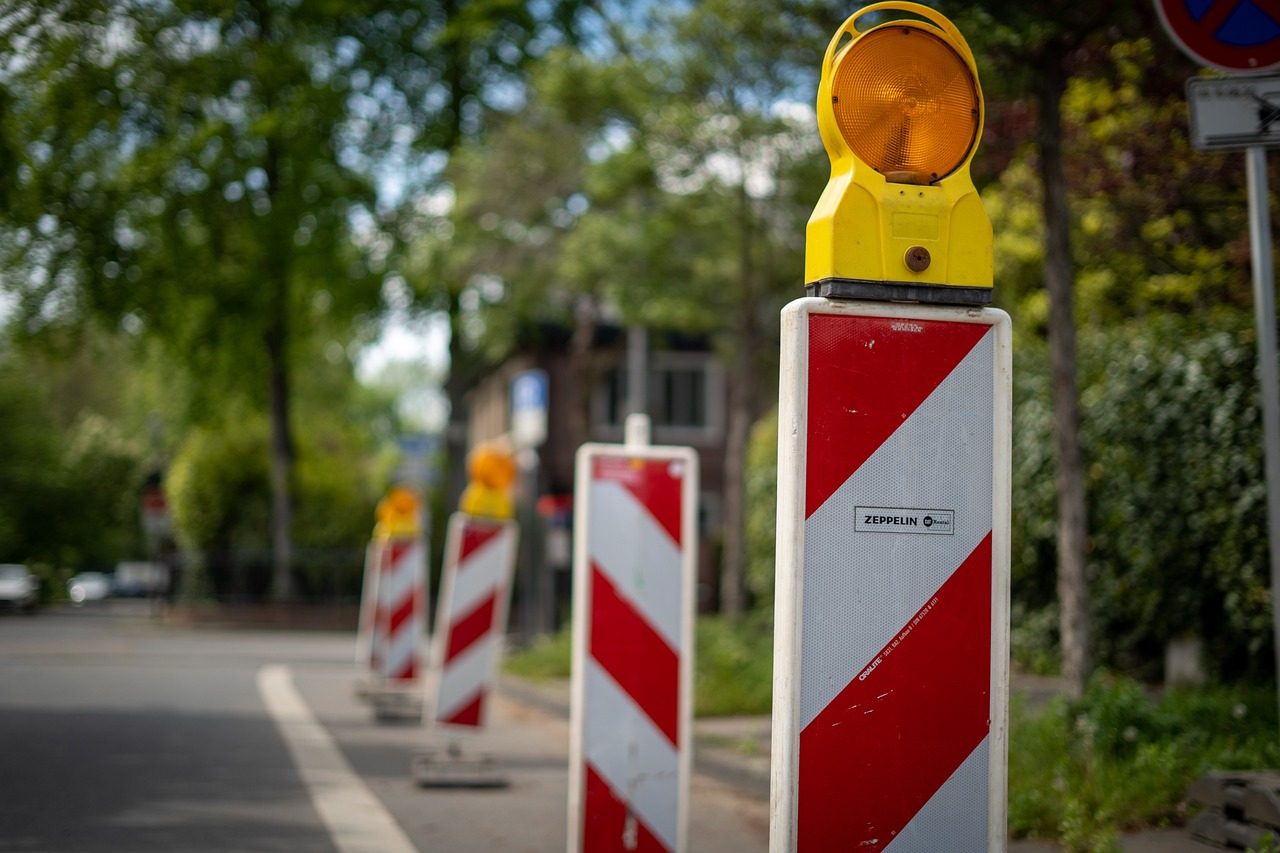 Czerwono białe znaki z pomarańczowym światłem ostrzegawczym, informujące o robotach drogowych