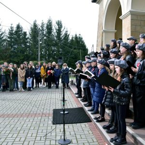 Na zdjęciu grupa dzieci stojąca na schodach prowadzących do kościoła. Na drugim planie młodzież i osoby dorosłe.