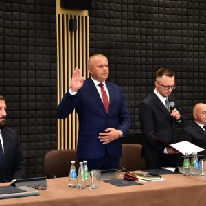 Na zdjęciu czterech mężczyzn. Jeden z nich unosi prawą rękę w górę i składa ślubowanie.