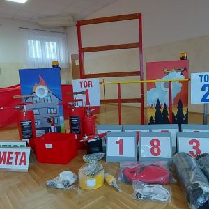 Elementy toru przeszkód do ćwiczeń dla strażaków rozłożone na parkiecie
