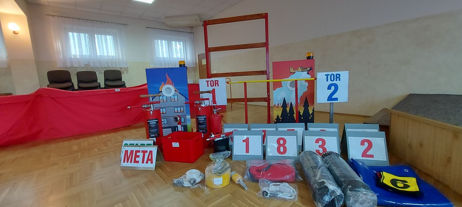 Elementy toru przeszkód do ćwiczeń dla strażaków rozłożone na parkiecie