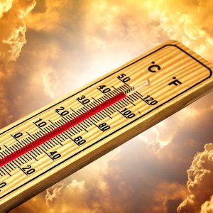 termometr wskazujący wysoką temperaturę na tle chmur oświetlonych słońcem