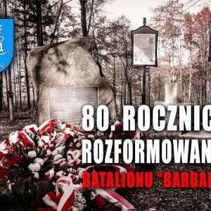 Napis "80 rocznica rozformowania batalionu Barbara". W tle pomnik z kamienia, pod którym położone są wiązanki kwiatów.