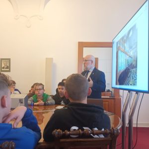 Uczniowie słuchają opisu do prezentacji wyświetlonej na tablicy multimedialnej
