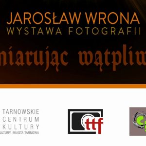 Tekst "Jarosław Wrona Wystawa Fotografii. Wymiarując Wątpliwość" na czarnym tle. Poniżej trzy logotypy.