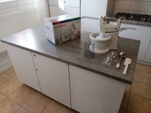 Sprzęty małego AGD oraz łyżki na blacie wyspy kuchennej.