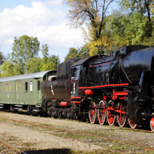 Czarny parowóz ciągnie cztery wagony pasażerskie