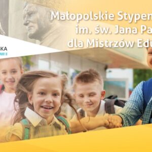 Czworo roześmianych dzieci biegnie obok budynku, w tle fragment pomnika Jana Pawła II