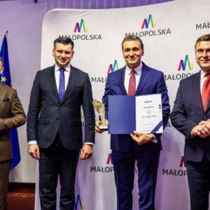Wójt Gminy Pleśna trzyma statuetkę i dyplom