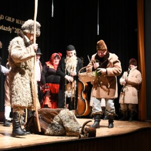 Pastuchy stoją nad turoniem, który upadł. W tle baba i żyd.
