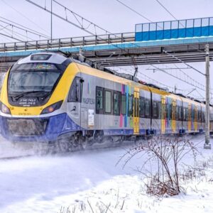 Pociąg Kolei Małopolskich przejeżdża pod kładką dla pieszych