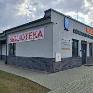 Wejście do budynku ośrodka Relaks, na ścianie wywieszony czerwony napis "biblioteka"