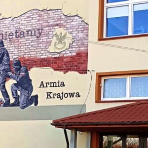 Fragment ściany placówki oświatowej z widocznym muralem przedstawiającym żołnierzy Armii Krajowej.