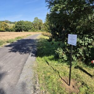 Nowa nakładka asfaltowa na drodze, z prawej strony znak informujący o dofinansowaniu i hydrant